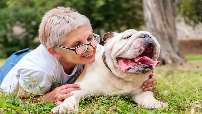 Retiree walking a happy dog in a park, enjoying pet care for retirement income strategies over 55—fun cash after 55