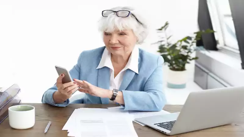 Retiree on a phone completing a survey for retirement income strategies over 55—earn after 55 easily